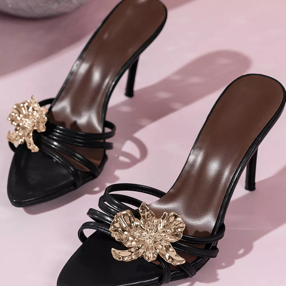 Black high heel sandals with gold floral embellishments and thin straps.