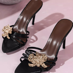 Black high heel sandals with gold floral embellishments and thin straps.