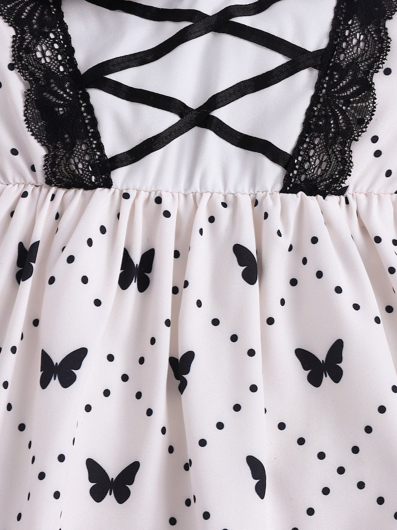 Baby dress with butterfly print, polka dots, black lace trim, and crisscross ribbon detail.