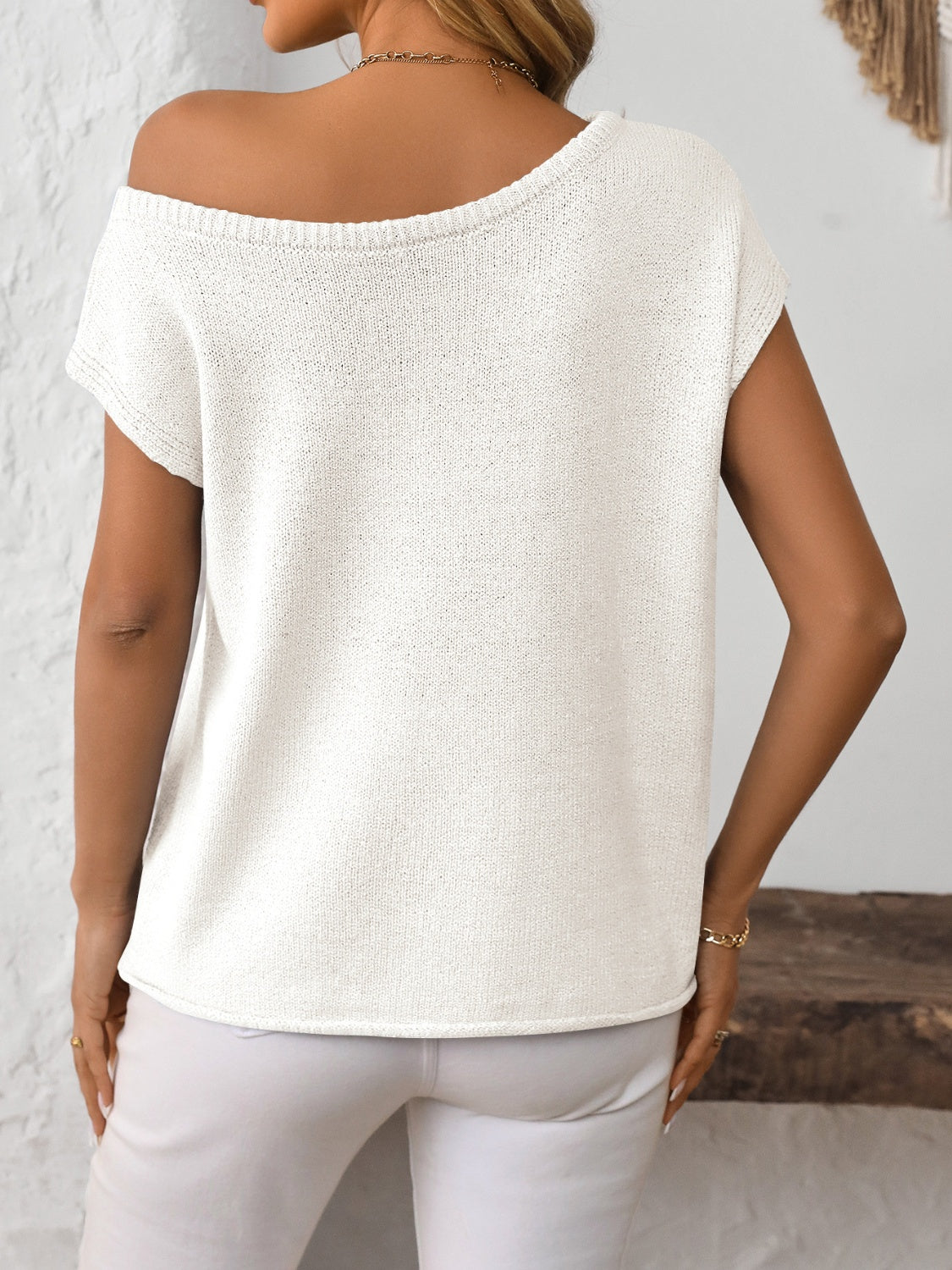 White off-the-shoulder knit tee with short sleeves and a boat neckline.