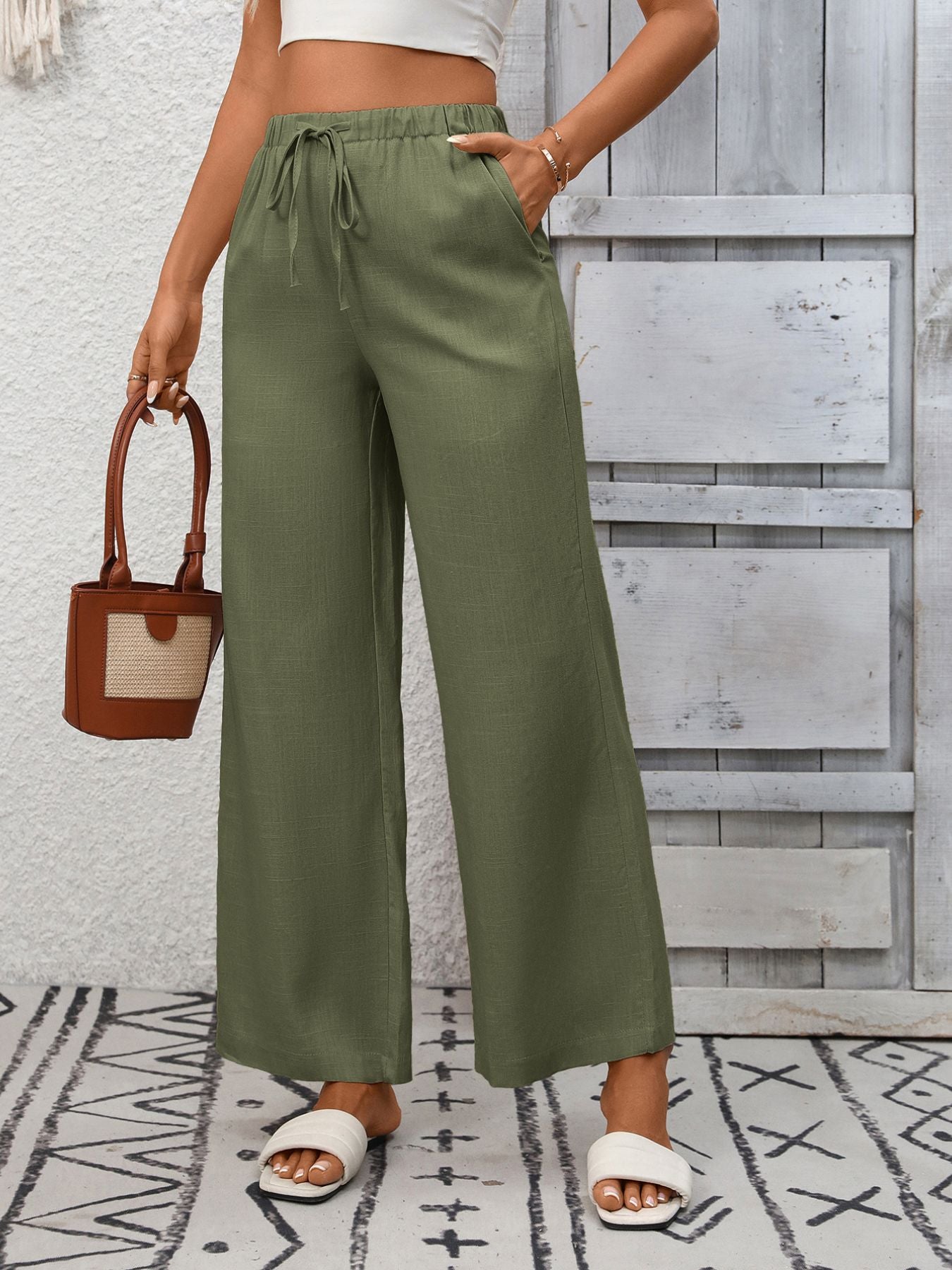 Army green wide-leg drawstring pants with pockets, styled with a white top and sandals.