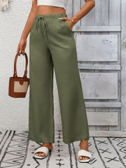 Army green wide-leg drawstring pants with pockets, styled with a white top and sandals.