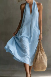 Light blue halter midi dress with V-neck and large front pockets, shown with a woven bag.