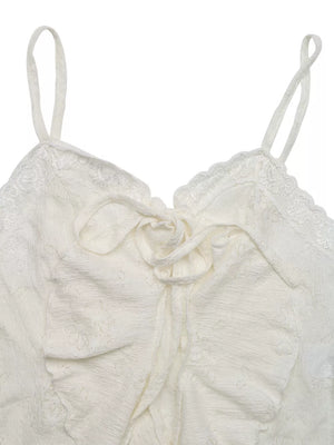 White lace tie-front camisole with ruffled hem and delicate floral pattern.