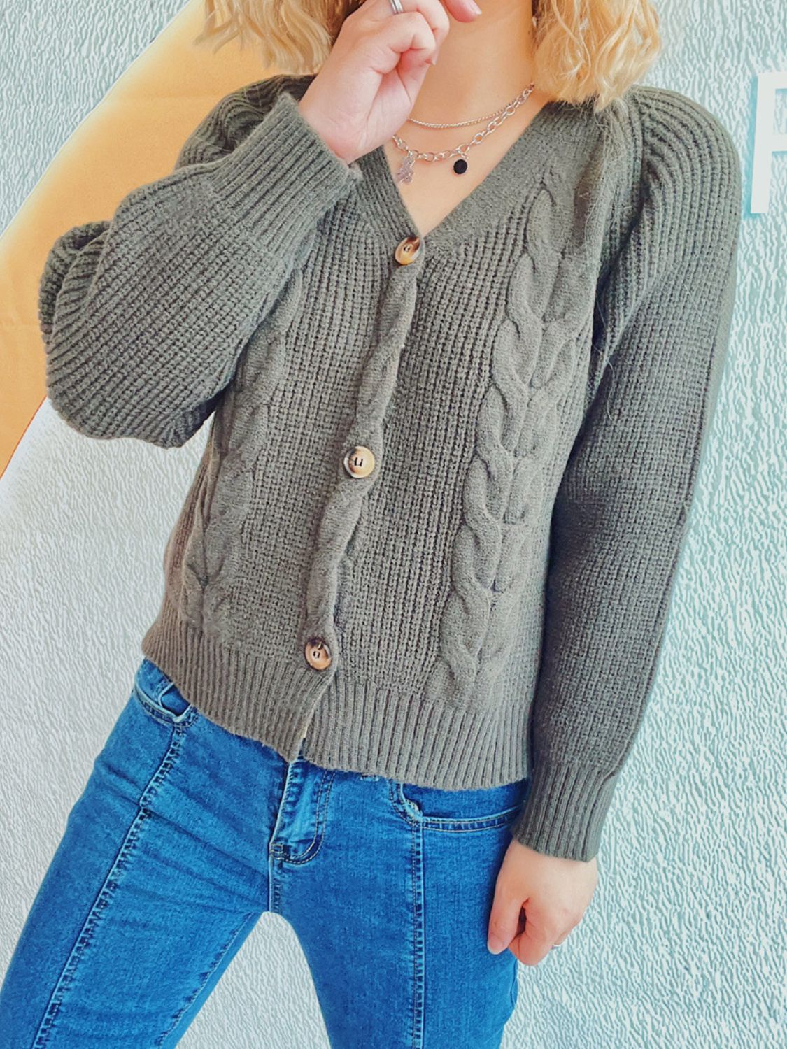 Sage cable knit raglan cardigan with button front and puff sleeves.