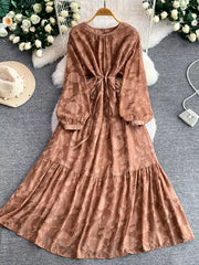Embroidered tie-waist dress in rust with long sleeves and tiered skirt.