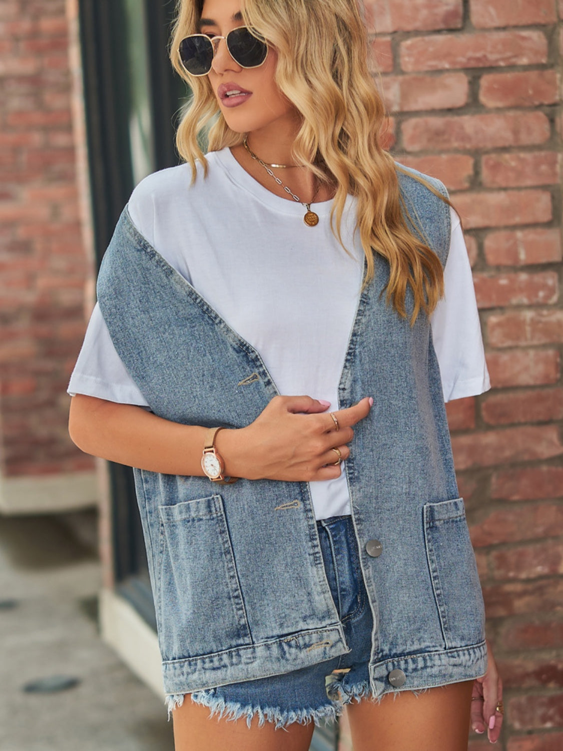 Medium wash denim vest with patch pockets and button front, worn over a white tee.