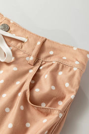 Polka dot maternity trousers in peach with white dots, drawstring waist, and wide leg cut.