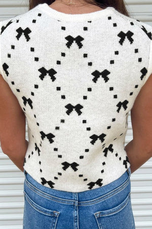 White knit tank sweater with black diamond bow pattern.