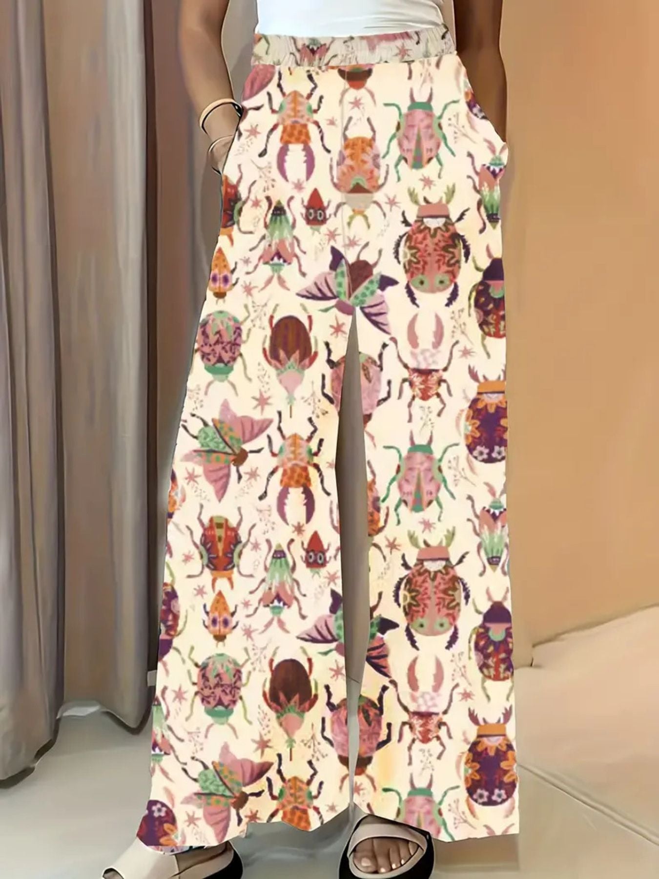 Whimsical print wide-leg maternity trousers in pastel yellow with a colorful beetle pattern.
