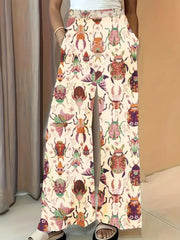Whimsical print wide-leg maternity trousers in pastel yellow with a colorful beetle pattern.