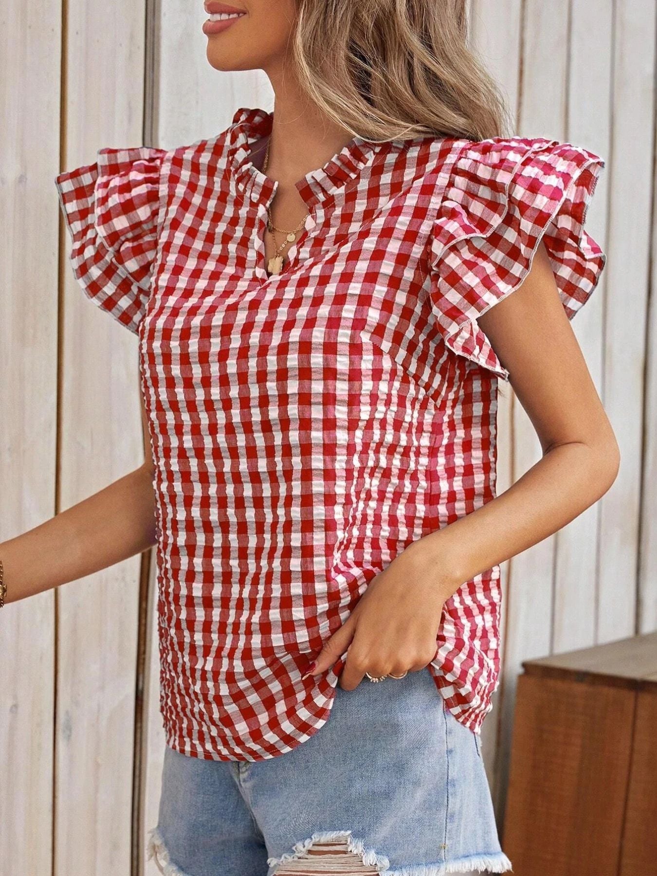 Red and white gingham blouse with ruffle sleeves and a gathered neckline.