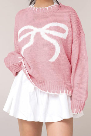 Graphic bow knit crewneck sweater in blush pink with white contrast stitching and neckline.