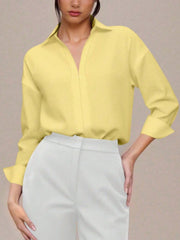 Yellow collared long sleeve bodysuit with a V-neck, cuffed sleeves, and a button-down front, styled with white pants.