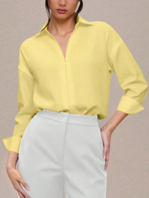 Yellow collared long sleeve bodysuit with a V-neck, cuffed sleeves, and a button-down front, styled with white pants.