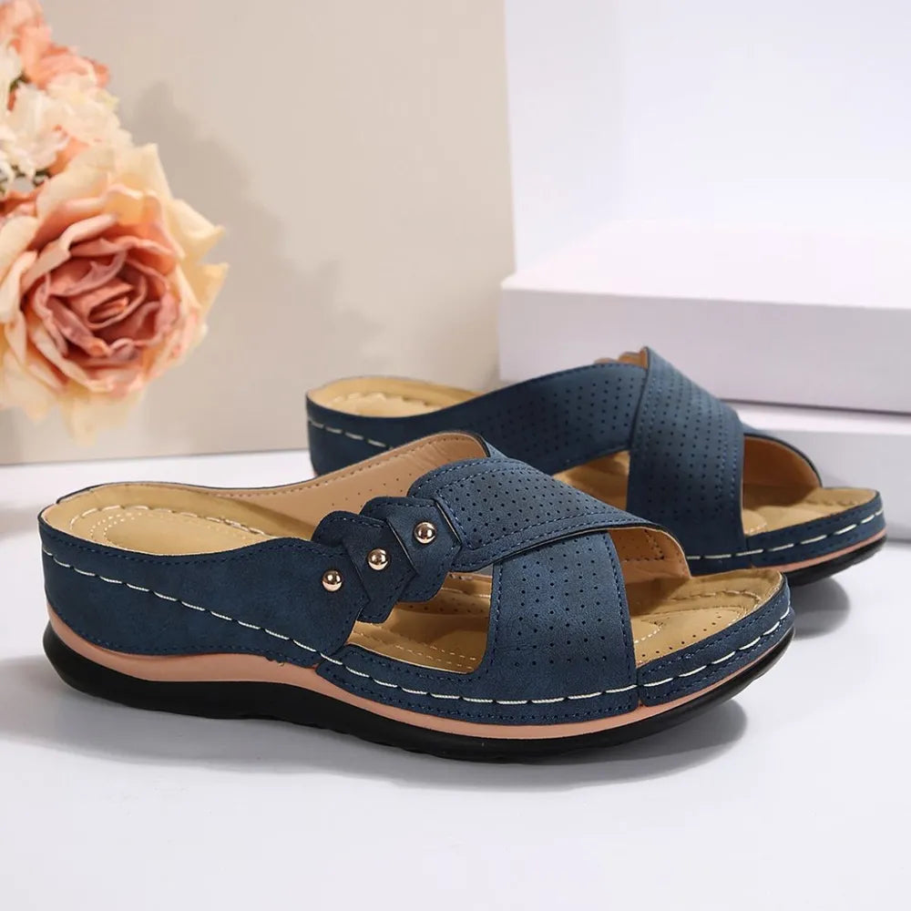 French Blue perforated cross-strap comfort sandals with decorative studs and white stitching.