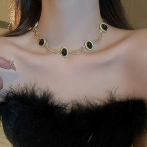 Gold oval gemstone necklace with layered chains and ornate detailing.