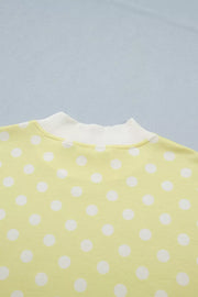 Pastel yellow polka dot polyester top with white ribbed neckline.