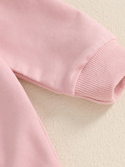 Pink cotton baby outfit with ribbed cuffs and bunny applique detail.