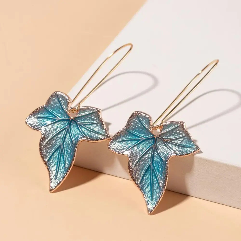 Sky blue enamel leaf drop earrings with gold-tone hooks.
