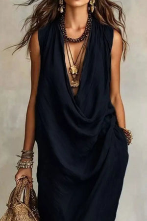 Black cowl neck midi dress with pockets and layered necklaces.