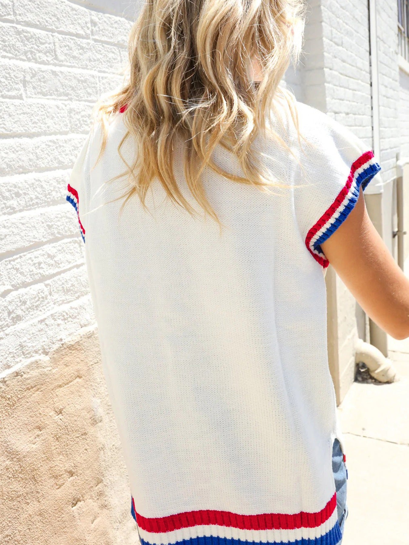 White knit sweater vest with red, white, and blue striped trim on sleeves and hem.
