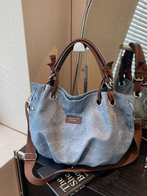 Blue slouchy crossbody bag with brown leather straps and adjustable strap.