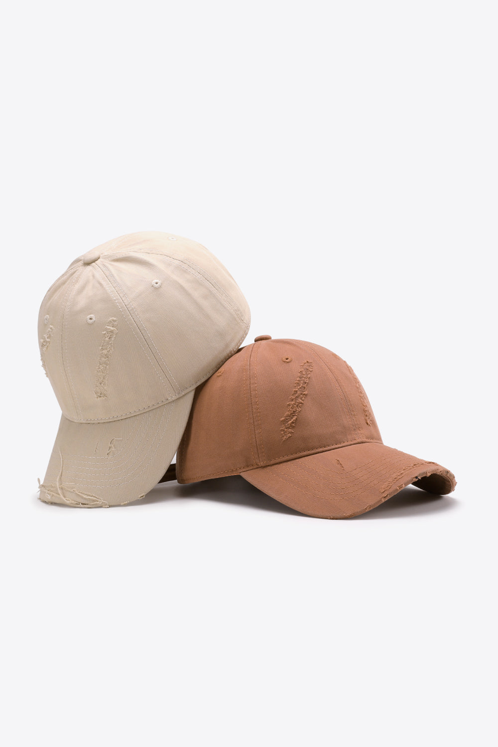 Two distressed baseball caps, one cream and one tan, with frayed details.