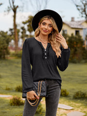Black ruffled henley blouse with button detail and long sleeves.