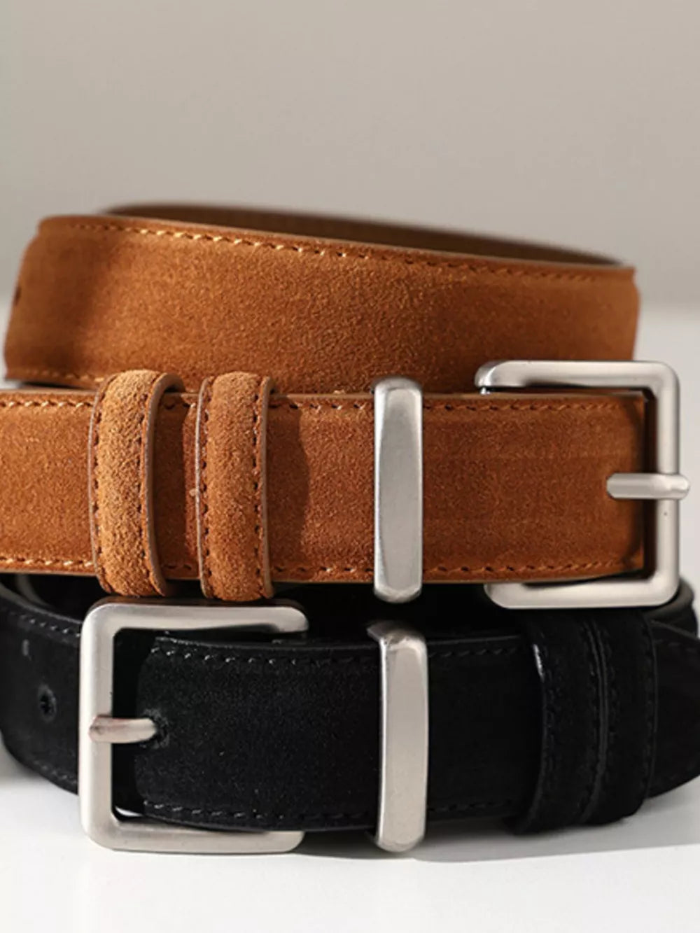 Suede leather belts with silver buckles in black and brown colors.
