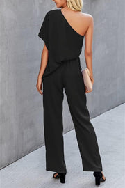 Black asymmetric drape-sleeve wide-leg jumpsuit with cinched waist.