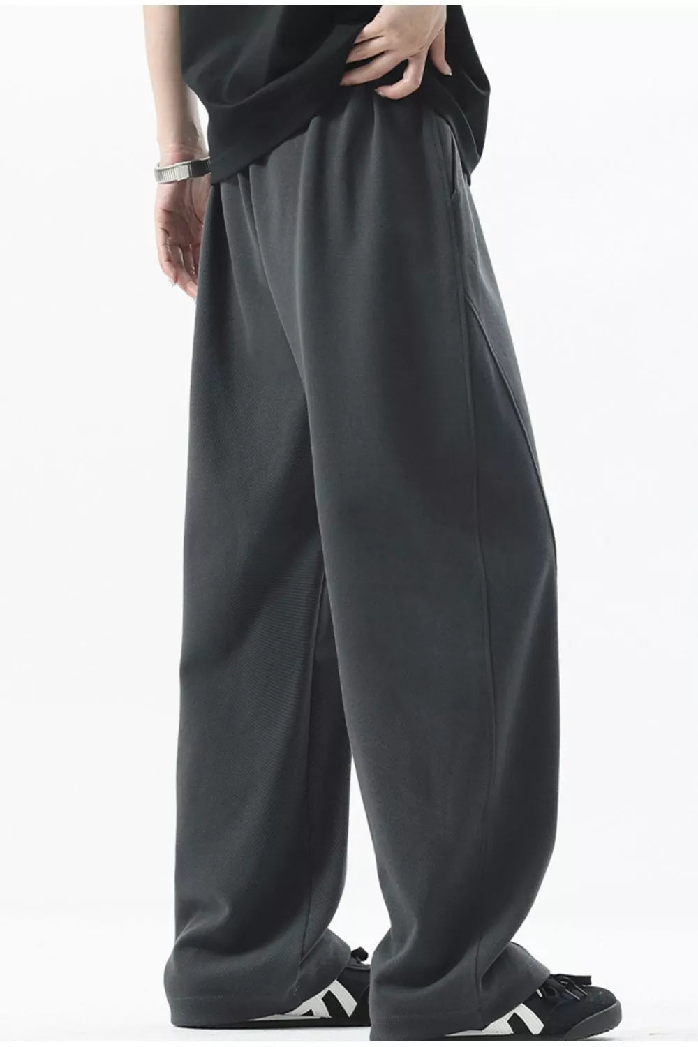 Men's dark gray loose fit sweatpants with side pockets and ribbed texture detail.