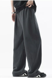 Men's dark gray loose fit sweatpants with side pockets and ribbed texture detail.