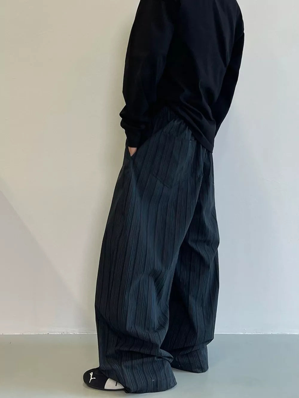 Men's dark grey wide-leg sweatpants with vertical texture and pockets.