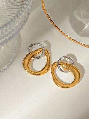 Two-tone sculptural asymmetric hoop earrings in gold and silver.