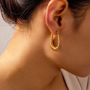 Gold coiled oval hoop earrings with a textured finish.