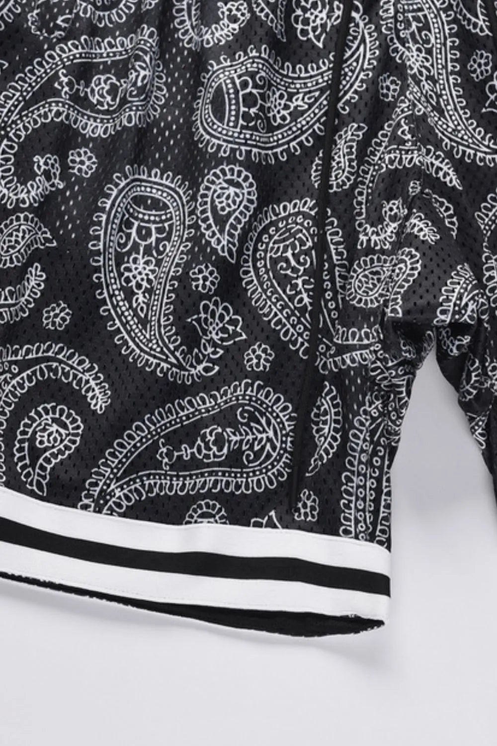 Black mesh basketball shorts with white paisley pattern and striped hem.