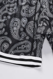 Black mesh basketball shorts with white paisley pattern and striped hem.