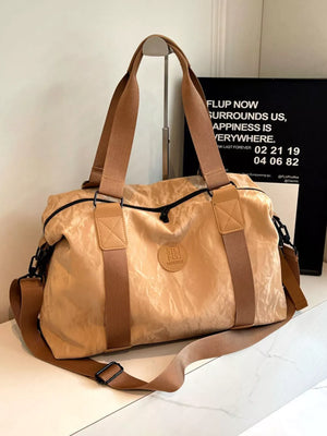 Chic tan oxford cloth travel bag with dual handles and adjustable shoulder strap.