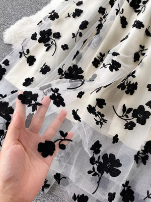 Maternity dress with sheer black floral overlay on ivory lining, showing texture.