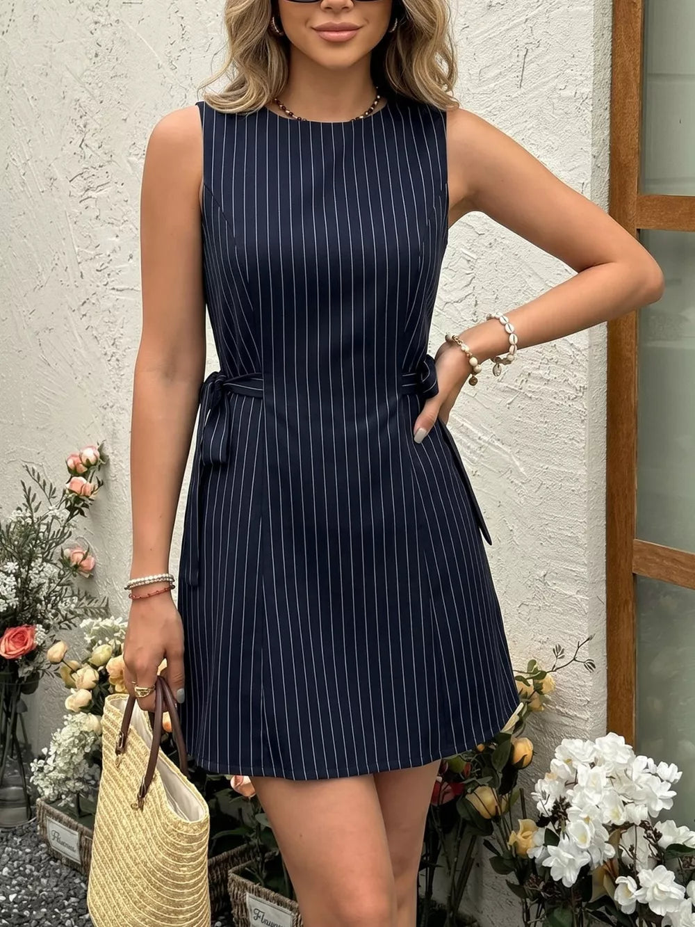 Navy striped tie-waist a-line dress with a round neckline and sleeveless design.