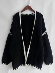 Black oversized knit cardigan with white contrast stitching detail on edges and sleeves.