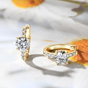 Gold pavé-set moissanite huggie hoop earrings with a central round-cut stone.