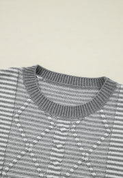 Gray and white geometric stripe knit sweater with crew neck.