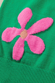 Green knit sweater with a pink floral applique and ribbed hem.