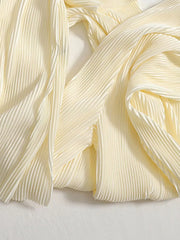 Elegant pleated two-piece set in apricot fabric with flowing texture.