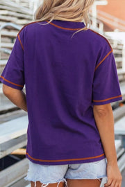 Purple cotton t-shirt with contrast orange stitching on neckline, sleeves, and hem.