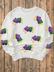 White sweatshirt with sequin Mardi Gras mask motif and gold ribbon detail.