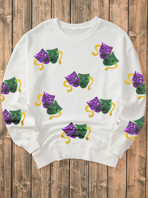 White sweatshirt with sequin Mardi Gras mask motif and gold ribbon detail.