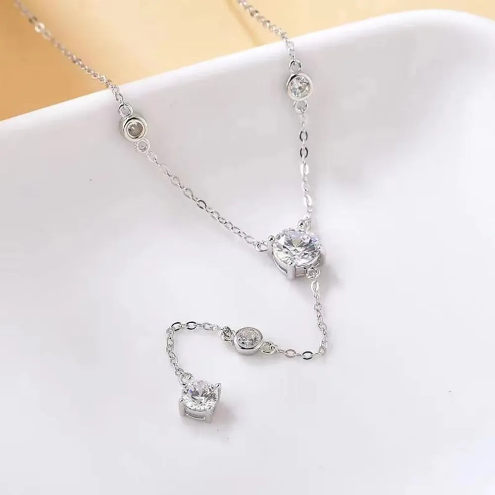 Silver lariat necklace with moissanite drop details and bezel-set stones.